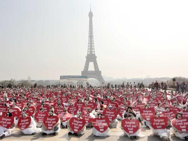 People take part in a flash mob event organized by the 'Alliance VITA' association as part of their tour of France in solidarity with elderly people and against euthanasia in front of the Eiffel tower in Paris. Events take place in 50 French cities from March 5 to May 4, 2012. The placards read 'To care is not to kill'. AFP Photo/Kenzo Tribouillard