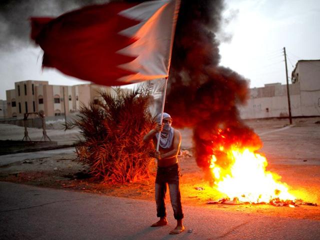 An anti-government protester waves Bahrain's national flag during clashes with riot police in the district of Sitra in Bahrain. Demonstrators were protesting in Sitra against the government holding the F1 Grand Prix in April. Reuters/Ahmed Jadallah