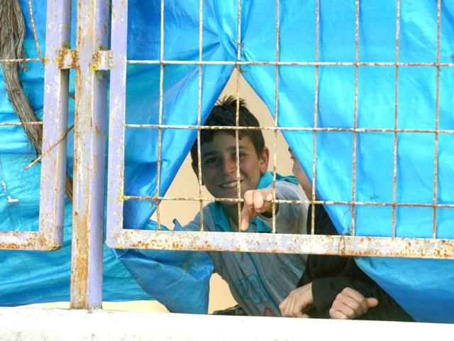 Syrian refugee children play behind a fence at the refugee camp in Yayladagi. AFP/Adem Altan