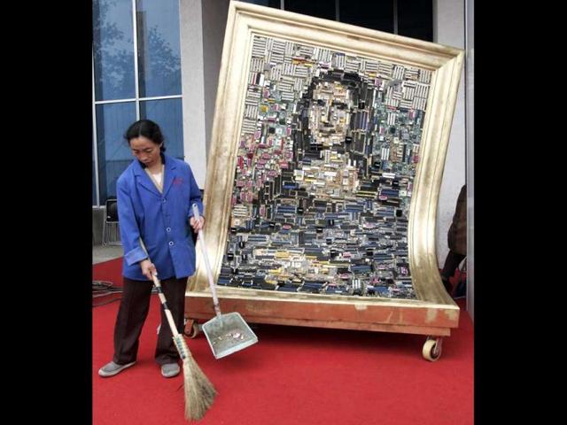 A cleaner sweeps beside a Mona Lisa artwork made from hundreds of used computer parts displayed at the '9th China Beijing International High-Tech Expo' in Beijing. The Leonardo da Vinci-inspired piece is titled 'Technology Smiling'. (Reuters) 