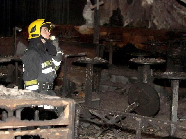 A firefighter inspects damage in a nightclub in Novi Sad after a fire broke out near the stage. Six persons, three young women and three men, died late on March 31 when the fire broke out at the Contrast nightclub. AFP PHOTO / ALEKSANDAR KAMASI