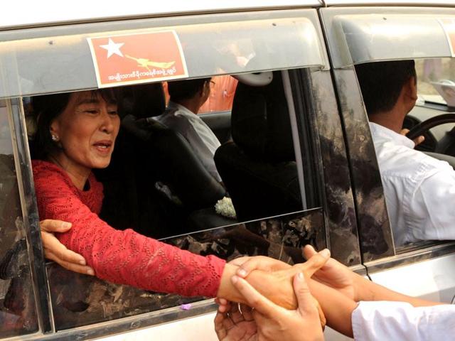Myanmar opposition leader Aung San Suu Kyi greets supporters as she travels through the constituency where she stands as a candidate in Kawhmu. Voting began in Myanmar elections seen as a test of the government's budding reforms, with opposition leader Aung San Suu Kyi standing for a seat in parliament for the first time. AFP PHOTO/Christophe ARCHAMBAULT