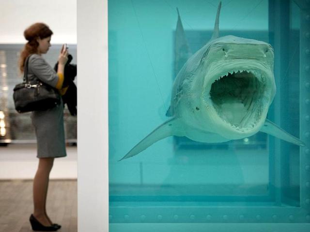 A woman looks at a creation by British artist Damien Hirst entitled The Physical Impossibility of Death in the Mind of Someone Living 1991 during the opening of his solo exhibition showcasing work spanning over two decades at the Tate Modern in central London. AFP Photo/Ben Stansall