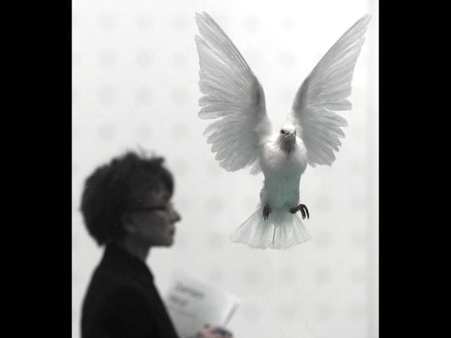 A woman walks by a work of British artist Damien Hirst entitled The Incomplete Truth 2006 during the launch of his solo exhibition showcasing work spanning two decades at the Tate Modern in central London. AFP Photo/Carl Court