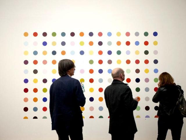 People look at British artist Damien Hirst's 1986 piece Spot Painting, household gloss on board, during a media preview of the first substantial show of his work in the UK at the Tate Modern gallery in London. AP Photo/Matt Dunham
