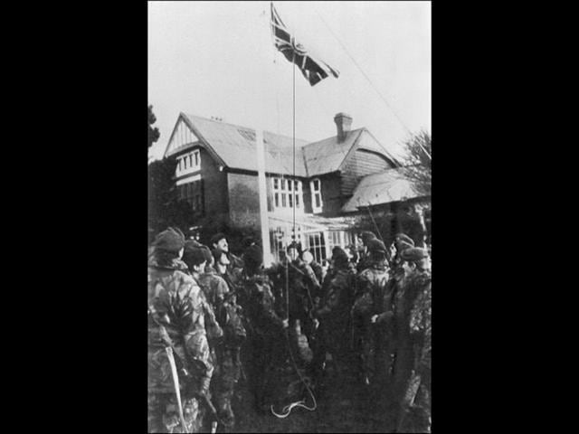British soldiers raise the Union Jack flag at Government House in Port stanley 17 June 1982 after the surrender of Argentine forces ending the Falklands war between Britain and Argentina.
