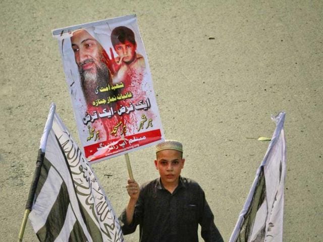A supporter of the banned Islamic organization Jamaat-ud-Dawa holds a party flag and an image of al Qaeda leader Osama bin Laden during an anti-American rally in Lahore May 15, 2011. Reuters/Mohsin Raza