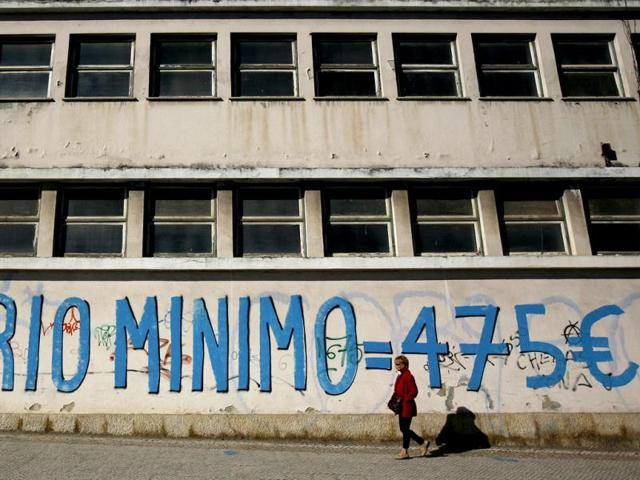 A woman walks past a graffiti reading "Minimum Wage = 475 euro" in Lisbon. A deepening economic slump propelled Portugal's jobless rate to a record 14 % at the end of 2011, as employers slashed jobs ahead of labour reforms and deeper spending cuts under the country's aid programme. The jump pushed the fourth quarter unemployment rate above the 13.7 % level envisaged for this year under the 78-billion-euro bailout, raising further challenges for the government in its quest to cut spending and raise taxes to meet strict fiscal goals. In the third quarter the rate stood at 12.4 %, the National Statistics Institute said. REUTERS/Rafael Marchante