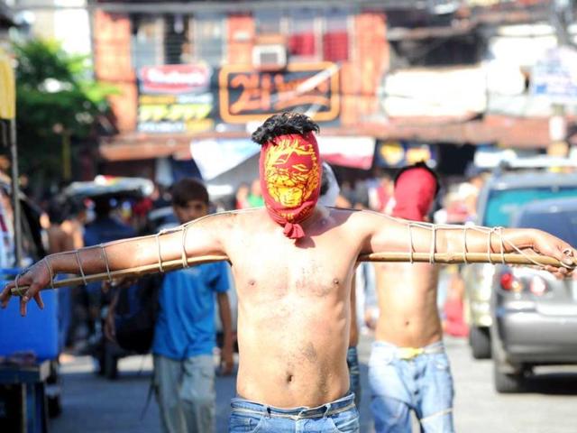 Penitents with their hands tied to a bamboo pole walk through the streets as part of Lenten observance in Manila. (AFP photo/Ted Aljibe)