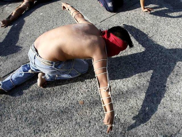 A hooded penitent lay prone on the pavement during flagellation ritual to atone for their sins in observance of Holy Week at Mandaluyong city, east of Manila, Philippines. AP Photo/Bullit Marquez