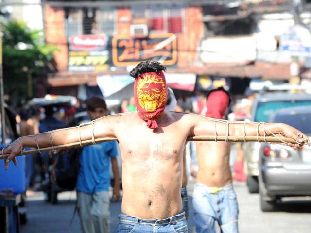 Penitents with their hands tied to a bamboo pole walk through the streets as part of Lenten observance in Manila. AFP Photo/Ted Aljibe.