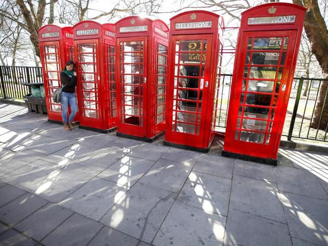 A tourist poses for a photo next to four telephone boxes next to Hyde Park, in central London. Reuters/Andrew Winning, Files