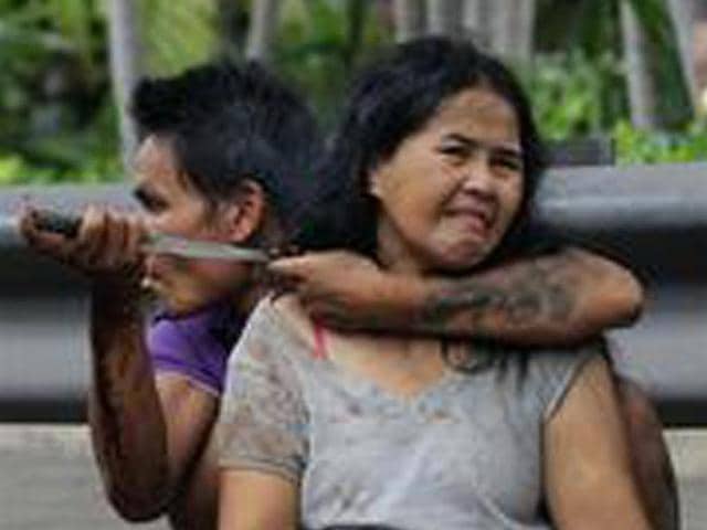 Sakdawut Hamsiri, 30, holds a knife against his wife Thawee Naiyanit on a street in Bangkok, Thailand. The 6-hour knifepoint hostage ended when the police used a Taser gun to electroshock him and took him to the police station. Police said the man was under the influence of drugs. (AP Photo/Sakchai Lalit)