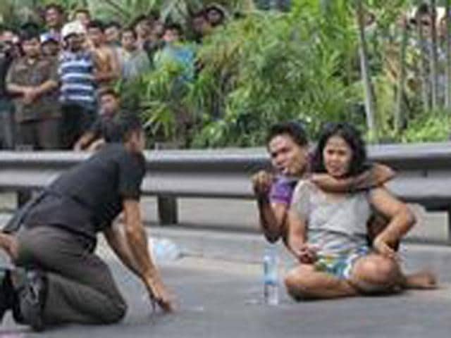 A Thai policeman talks to Sakdawut Hamsiri, 30, who holds a knife against his wife Thawee Naiyanit on a street in Bangkok, Thailand. The 6-hour knifepoint hostage ended when the police used a Taser gun to electroshock him and took him to the police station. Police said the man was under the influence of drugs. (AP Photo/Sakchai Lalit)