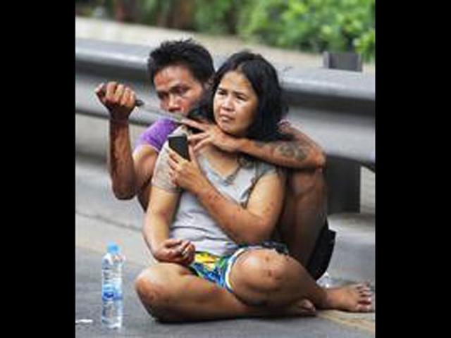 Sakdawut Hamsiri, 30, holds a knife against his wife Thawee Naiyanit on a street in Bangkok, Thailand. The 6-hour knifepoint hostage ended when the police used a Taser gun to electroshock him and took him to the police station. Police said the man was under the influence of drugs. (AP Photo/Sakchai Lalit)