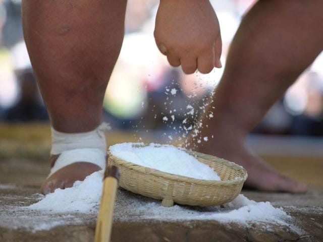 A sumo wrestler picks up a handful of salt to throw into the ring before his bout for luck in Tokyo. AFP/Richard A Brooks
