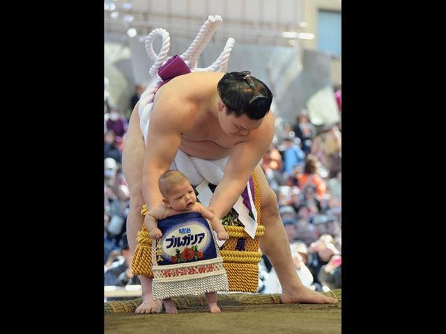 'Yokozuma' or grand champion Hakuho of Mongolia holds his child in the ring as he jokes around for the crowd before taking part in a sumo exhibition at Yasukuni shrine in Tokyo. AFP/Richard A Brooks