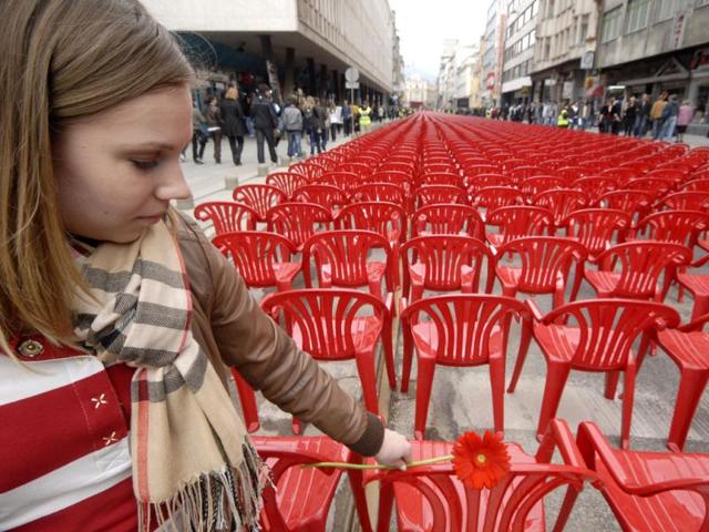 Bosnian girl lays flower on red chairs displayed along main street in Sarajevo to mark the 20th anniversary of the start of the Bosnian War. City officials have lined up 11,541 red chairs arranged in 825 rows along the main street that now looks like a red river. AP Photo/Sulejman Omerbasic