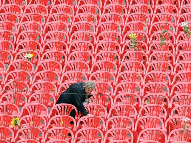An elderly woman leaves a flower on some of 11,451 empty chairs on the main street of Sarajevo. More than 11,000 red chairs, symbolizing 11541 victim of the siege, lined Sarajevo's main avenue as Bosnians marked the 20th anniversary of the bloodiest conflict in Europe since World War II with songs and remembrance. AFP Photo/Elvis Barukcic