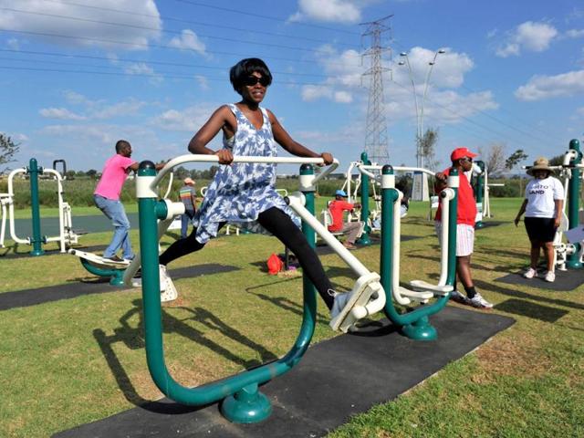 People work out at new outdoor gym in Soweto. Opened by the Johannesburg city council a month ago, the gym has seen the people of all ages pumping iron and swaying around in swing-like contraptions designed to target problem fat. AFP