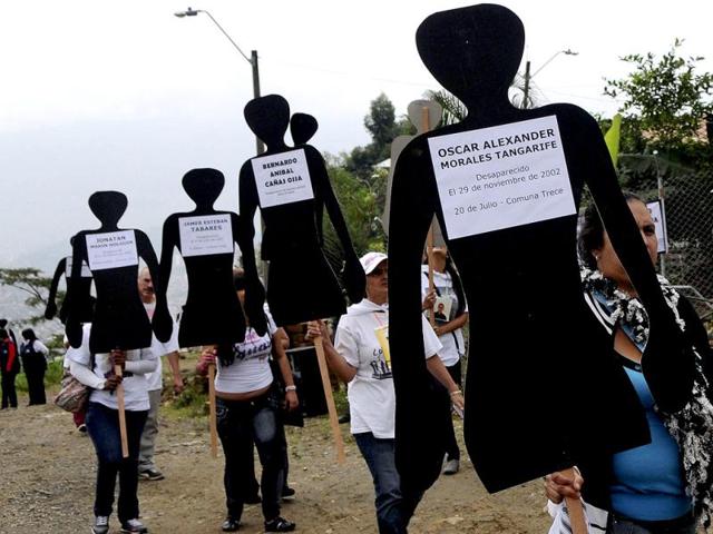 Activists and relatives hold cardboard silhouettes representing disappeared people as they walk during the National Day of Memory and Solidarity with Victims in Medellin, Colombia. AP/Luis Benavides
