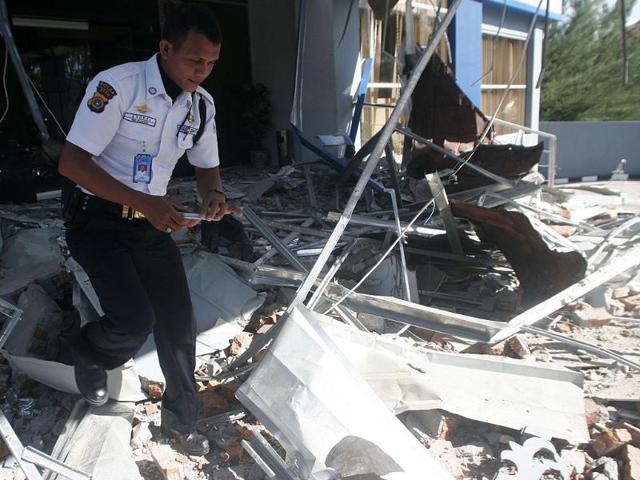 A security officer walks through debris from the strong earthquake at an office building in Banda Aceh, Sumatra island. AP/Heri Juanda