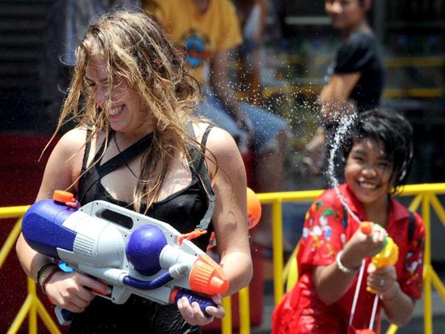 A Thai teenager squirts a tourist with water during the Songkran Festival along the famous travellers' area of Khao San Road in Bangkok. Songkran is the Thai New Year which starts on April 13 this year during which people celebrate by splashing water at each other. AFP PHOTO / PORNCHAI KITTIWONGSAKUL