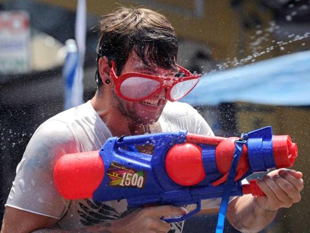 A tourist takes part in watergun battles during the Songkran Festival along the famous travellers' area of Khao San Road in Bangkok. Songkran is the Thai New Year which starts on April 13 this year during which people celebrate by splashing water at each other. AFP PHOTO / PORNCHAI KITTIWONGSAKUL
