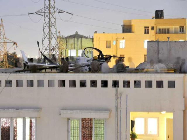 Police and fire department personnel, including Hindustan Aeronautics Limited officials, at dusk near a Schweizer helicopter that made an emergency landing on the rooftop of a residential building in Bangalore. (AFP Photo)