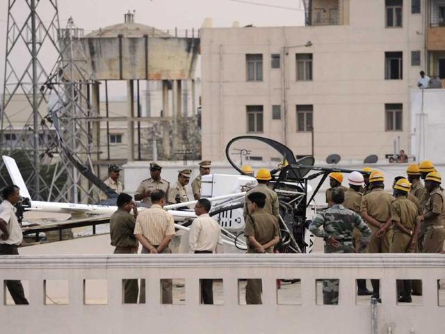 Police and fire department personnel, including Hindustan Aeronautics Limited officials, gather near a Schweizer helicopter that made an emergency landing on the rooftop of a residential building in Bangalore. (AFP Photo)