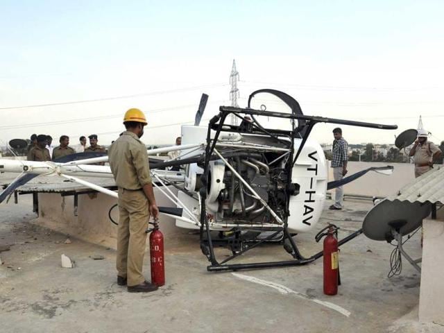 Firefighters are seen near a Schweizer helicopter that made an emergency landing on the rooftop of a residential building in Bangalore. (AFP Photo)