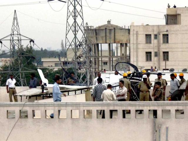 Police and other officials are seen near the helicopter of Hindustan Aeronautics Limited which made an emergency landing on the roof of an apartment in Byapanahalli area in Bengaluru. Both the pilot and the co-pilot escaped unhurt, police said. (PTI Photo)