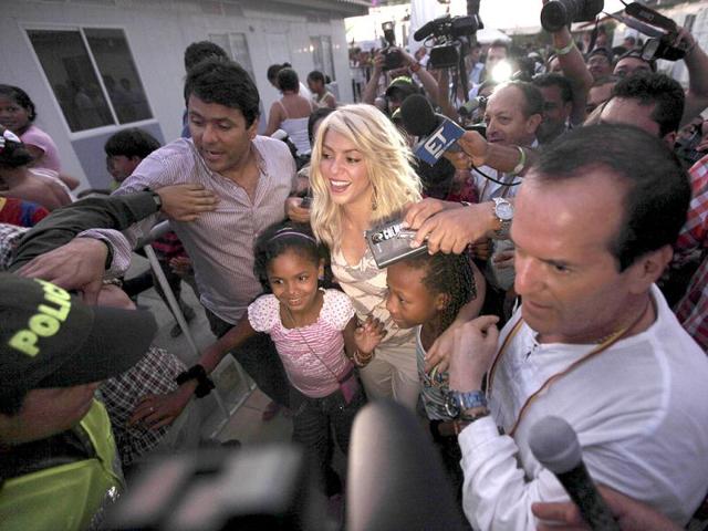 Surrounded by fans, Colombian singer Shakira, center, leaves after attending the inauguration of a child care center in Cartagena, Colombia. AP Photo/Fernando Llano
