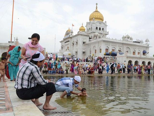 A devotee helps his child take a dip at Bangla Sahib Gurdwara on the occasion of Baisakhi in New Delhi. UNI
