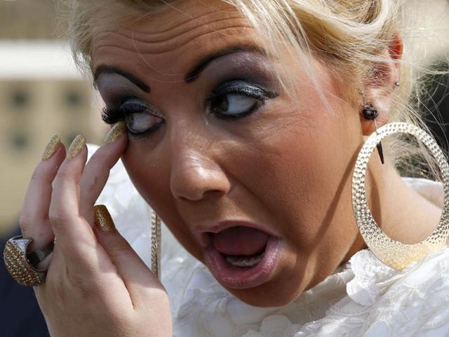 A racegoer adjusts her make-up as she arrives for Ladies' Day on the second day of the Grand National meeting at Aintree in Liverpool, northern England. Reuters/Phil Noble