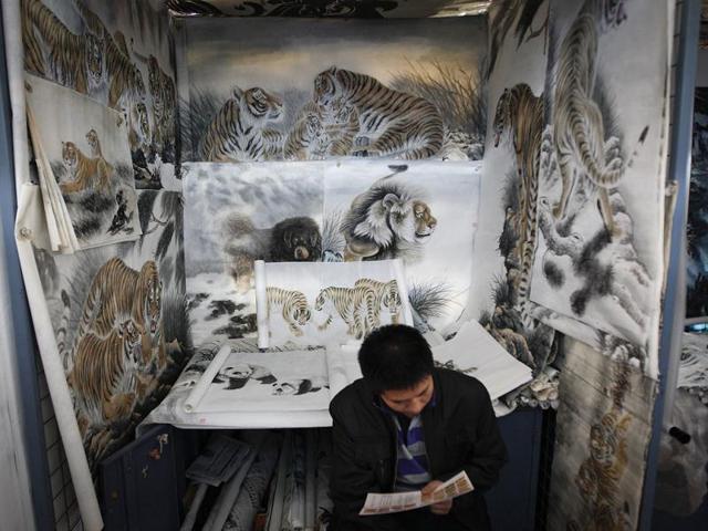 Vendors sit in front of Tiger painting display items for sale at Panjiayuan flea market in Beijing. AP Photo/Vincent Thian
