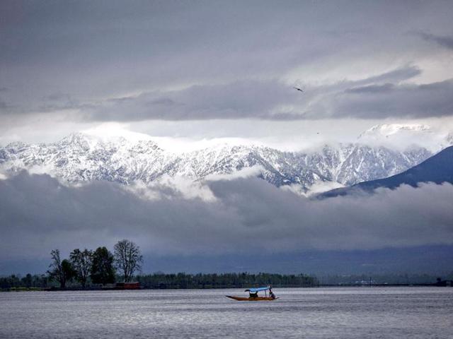 A Kashmiri boatman rows his shikara, a traditional wooden boat, with the backdrop of snow covered mountains as thick clouds hover at the Dal Lake on the outskirts of Srinagar. AP Photo/Dar Yasi