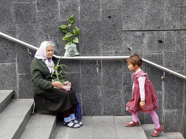 A girl walks next to an elderly woman selling plants at the entrance of a pedestrian subway in the centre of Kiev. Reuters/Konstantin Chernichkin