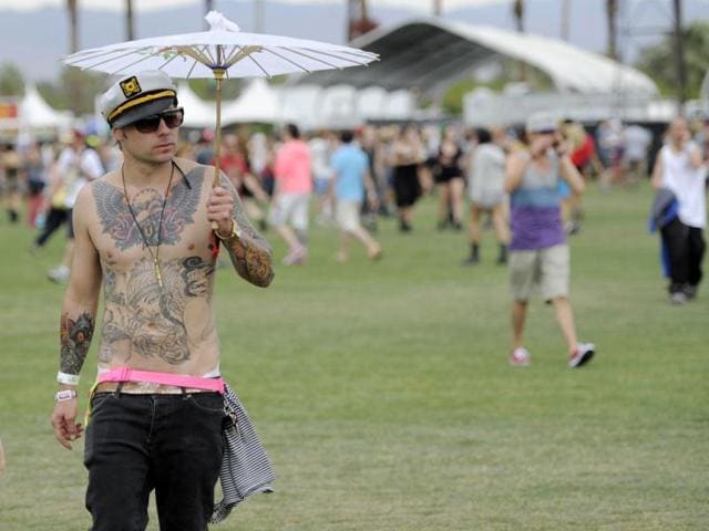 Justin Dalve, of Los Angeles, uses a parasol during light rain on the first weekend of the 2012 Coachella Valley Music and Arts Festival in Indio, California. (AP Photo/Chris Pizzello)