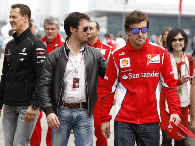 Fernando Alonso of Spain and Michael Schumacher walk down the F1 paddock with fans as they arrive at the circuit for the Chinese Formula One Grand Prix in Shanghai. (AP Photo/Andy Wong)