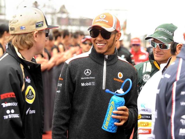 Lewis Hamilton chats to Lotus-Renault driver Kimi Raikkonen (L) and Caterham-Renault driver Heikki Kovalainen of Finland (R) as they head to the drivers parade before the start of the Chinese Grand Prix in Shanghai. (AFP Photo/Peter Parks)
