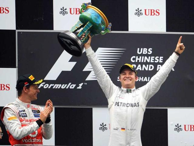 Nico Rosberg holds up the winner's trophy as third-placed Lewis Hamilton of Britain and second-placed Jenson Button of Britain applaud on the podium during the awards ceremony at the Shanghai International Circuit. (AFP/Liu Jin)
