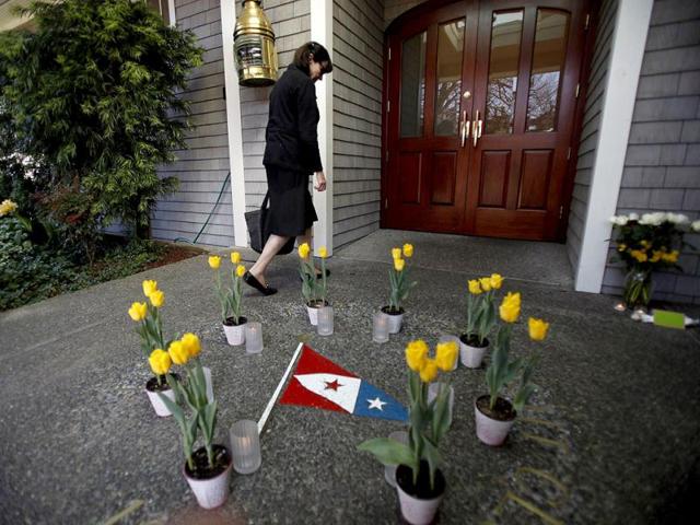 A woman walks past pots of flowers arranged in a circle as she enters San Francisco Yacht Club to attend a vigil for the four missing sailors in Belvedere, California. (Reuters/Stephen Lam)