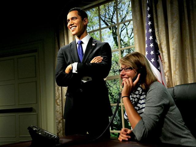 A visitor (R) pretends to talk on a phone alongside a wax figure of US President Barack Obama (L), on the opening day of the new Madame Tussauds exhibition in Sydney. (AFP Photo/Greg Wood)