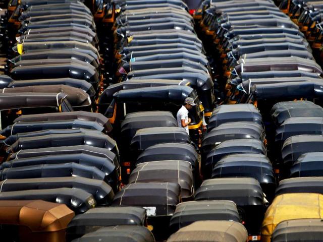 A pedestrian walks through parked three wheelers called auto rickshaws, during a strike in Mumbai. Auto rickshaw drivers went on a day long strike to protest against a lower than expected hike in fares. AP Photo/Rafiq Maqbool