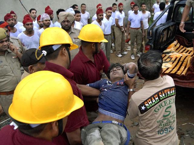 Rescue workers remove a worker from the debris of a collapsed factory in Jalandhar. (AP Photo/ Shammi Mehra)