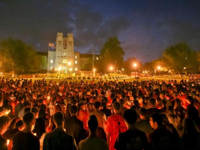 Virginia Tech students pass the flame of a memorial candle, on the Virginia Tech campus in Blacksburg. (AP Photo/The Roanoke Times, Daniel Lin)