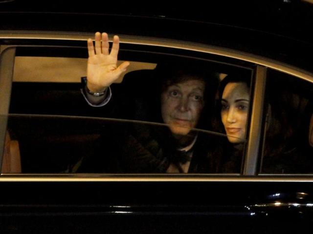 Singer Paul McCartney (L) greets from a car, as he sits beside his wife Nancy Shevall, after his arrival at the Silvio Pettirossi International Airport in Luque. (Reuters/Jorge Adorno)