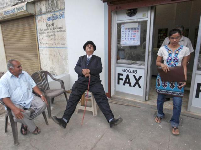 Ashok Aswani sits outside a shop along a pathway in Adipur in Gujarat. (Reuters/Danish Siddiqui)