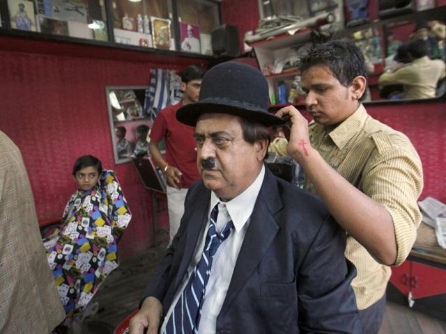 Ashok Aswani is helped by barber as he gets dressed up as Charlie Chaplin at a salon in Adipur in Gujarat (Reuters/Danish Siddiqui)